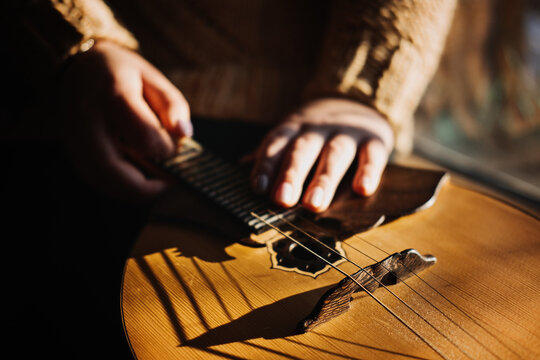 Domra Folk Musical Instrument. Female hands with 4 strings Natural Wood Handmade Musical Instrument Domra Close up