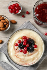 Delicious semolina pudding with berries on wooden table, flat lay