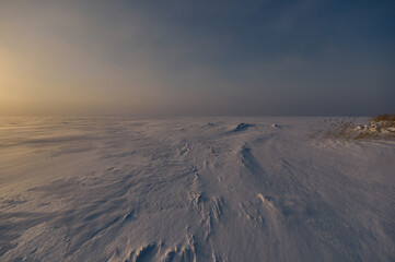 Sunset in vast space on big frozen lake, which looks similar to the icy wasteland