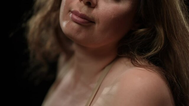 Close-up unrecognizable plus size woman in bra with long brunette hair blowing. Confident sensual seductive Caucasian lady at black background