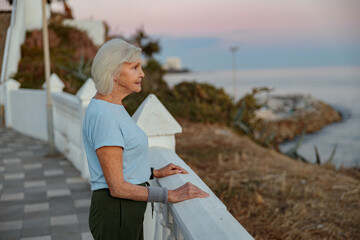 Caucasian good looking senior woman keeping fit and healthy during walking exercises in public park at sunrise