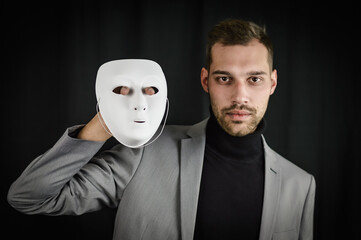 Be yourself - young man holding a white mask next to his face - concept for being real and not fake