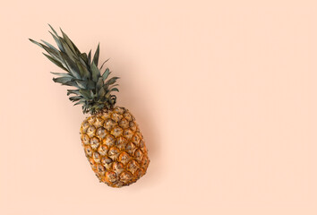 Juicy pineapple lying on a trendy soft beige pink background. Tropical ripe juicy fruit flat lay for your design projects. Minimalistic wallpaper