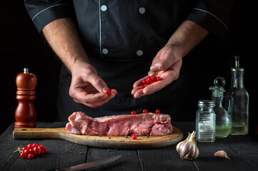 In the restaurant kitchen chef prepares raw calf meat. Before baking, the cook puts the viburnum on the beef. National dish