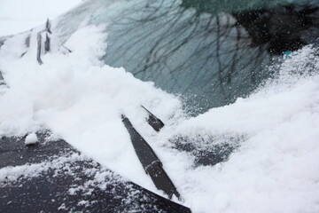 Car wipers on snowy windshield glass