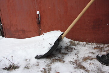 Snow shoveling with plastic shovel near the garage door in winter