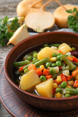 Bowl of delicious turnip soup on wooden table