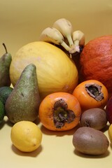 colorful fruits, fruits scattered on a yellow background, sharon, yellow melon, pear, bananas, kiwi, avocado, fresh vitamins