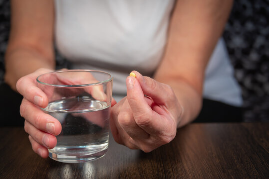 An Older Woman (old Lady) Is Taking Medication. An Elderly Lady, A Tablet And A Glass Of Water In Her Hands.