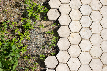 Concrete gray hexagon tiles, honeycomb tiles texture background, ground soil and grass weeds. Top...
