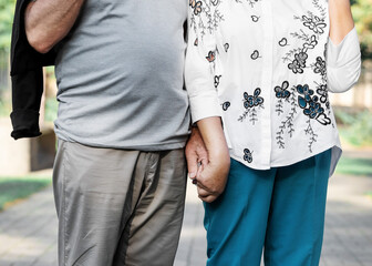 Lifestyle Cropped shot of elderly couple holding hands while standing together at park. Focus on hands.