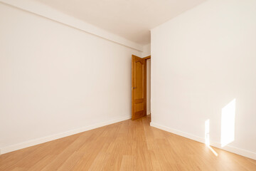 Large empty room with freshly painted walls with oak parquet floors and open door