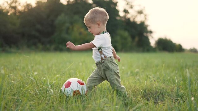 Happy family. Parents and children play football.People picnic on green grass in park.Family on lawn with soccer ball.Son and daughter have fun in summer field.Children playing ball together in park