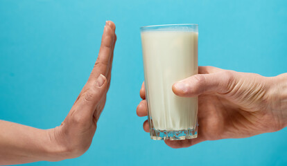 Lactose intolerance. Glass of milk and hand showing stop. - 477358935