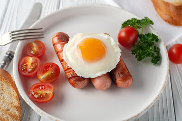 Scrambled eggs with sausages, tomatoes and toasts on a white wooden background