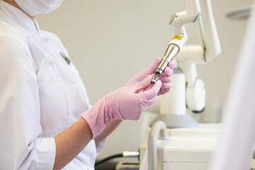 Woman doctor cosmetologist replaces the attachment on the cosmetology laser apparatus fotona in a...