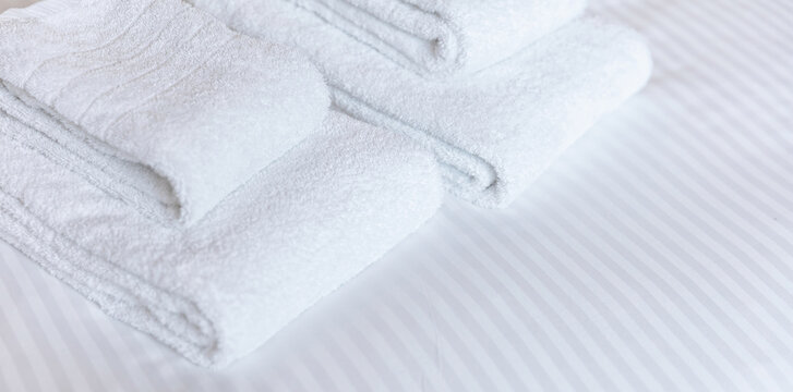 Fresh white towel on a hotel room bed, close up. Bedroom interior detail, comfort and hospitality
