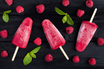 Top view of popsicles with raspberry on the black wooden  background. Close-up.