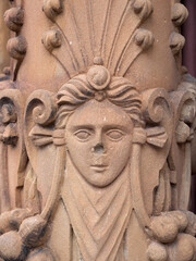 Relief eines Frauenkopfs auf einer Säule