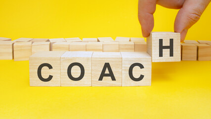 business man holds wooden blocks with the word Coach. the concept of achieving business goals....