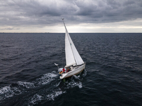 Aerial view of sailboat sailing on a cloudy and windy day near Oresund Bridge, Denmark.