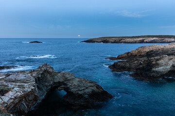 Full moon on the coast of Galicia, with lighthouse, natural rock arches, etc!