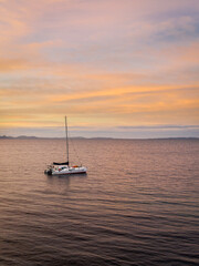 Fototapeta premium Catamaran au lever du soleil devant l'ile de Porquerolles sur la côte d'Azur - Catamaran with sunrise from the coastal path near Porquerolles - Azur Coast