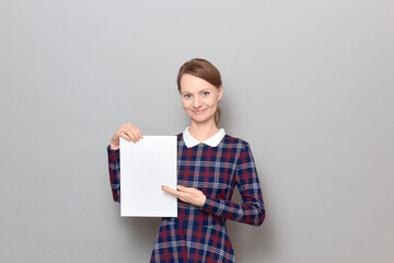 Portrait of happy young woman holding white blank paper sheet