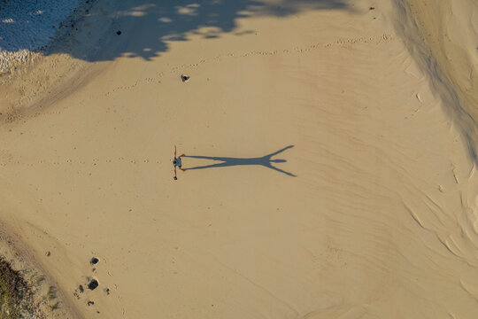 Aerial view of a person on the beach playing with shadows at l'Ilot Bernache, a small island along the coast near the reef, Mauritius.