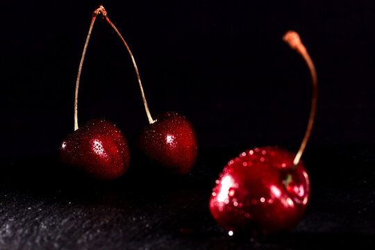 red cherries with water drops on black stone stand on a black background