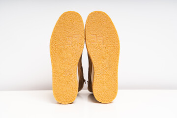 outsoles of two brown leather winter boots on a white background