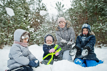 Mother with three children in winter nature. Outdoors in snow.