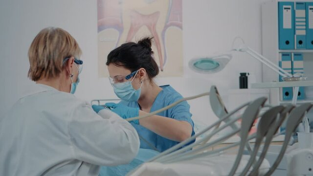 Nurse and stomatologist examining teeth of patient, using dental instruments to do drill procedure for oral care. Dentistry team doing denture inspection to treat man with caries.