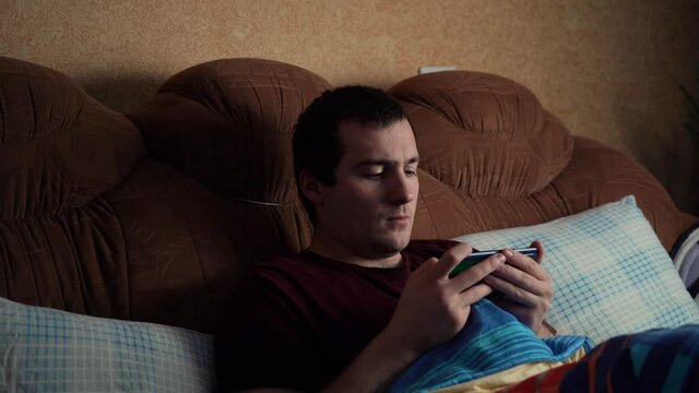 sick man playing the phone while lying on the bed