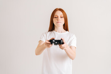 Studio portrait of pretty young woman playing video game with controller looking at camera on white isolated background. Happy lady using joystick on console enjoying online game.