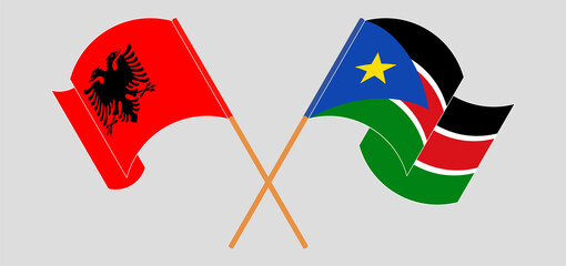 Crossed and waving flags of Albania and South Sudan