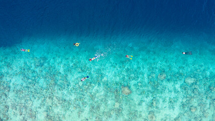 Aerial view of people snorkling a reef in the Maldives.