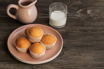 Freshly baked muffins and a jug of milk on a wooden table. Portion cupcakes. Sweet dessert