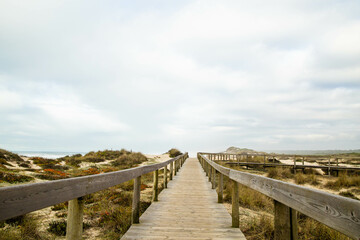 Wooden path with cloudy sky on Furadou beach in Portugal.