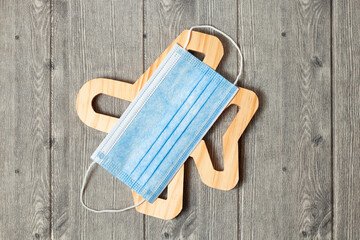Wooden plane with blue medical mask from above on gray background. Flat lay, top view.