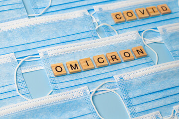 Blue medical masks lined with the letters of the new mutated coronavirus - Omicron. Tracking...