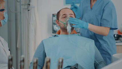 Patient with oxygen mask receiving anesthesic in dentistry cabinet, getting ready for stomatological procedure with dental tools and drill to polish caries. Oral care anesthesia on man.