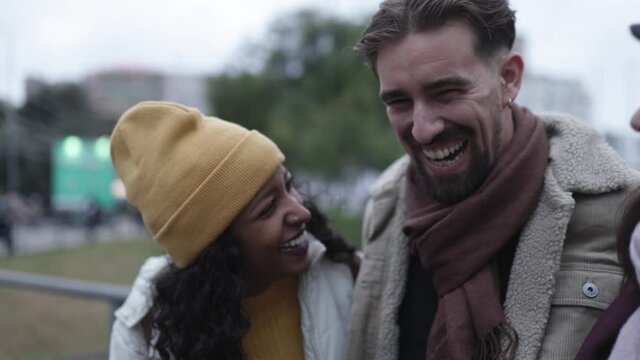 United three young multiracial friends laughing and having fun in winter at city street - Diverse group of millennial people enjoying together - Friendship concept. High quality 4k footage
