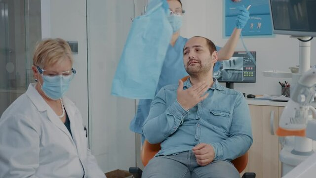 Stomatologist consulting patient with caries problem in dentistry office, using dental tools and instrument. Medic and assistant preparing for surgery procedure with drill intrument.