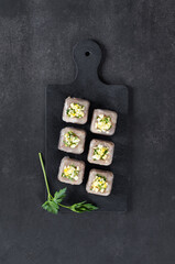 Traditional Russian cold appetizer. Pork jelly with pieces of meat in the form of small square portions with a filling of finely chopped egg and parsley, on a board on a dark background. Top view