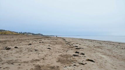 Broughty Ferry beach, Scotland, on an overcast day. Yellow sand in the foreground, blue sky and sea water in the background.