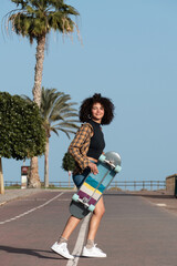 Happy young skater afro hair woman holding skateboard © 1 MEDIA