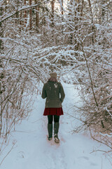 A young woman walking in snowy forest in winter time