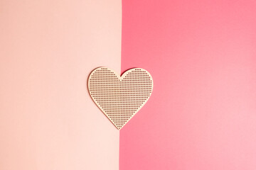 Wooden heart on a two tone pink background