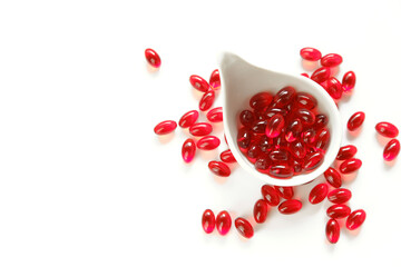 Krill oil red gelatin capsules in white cup on a white background.omega fatty acids.Healthy eating...